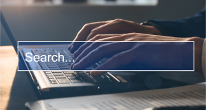 Hands typing on a laptop with a “Search…” text overlay.
