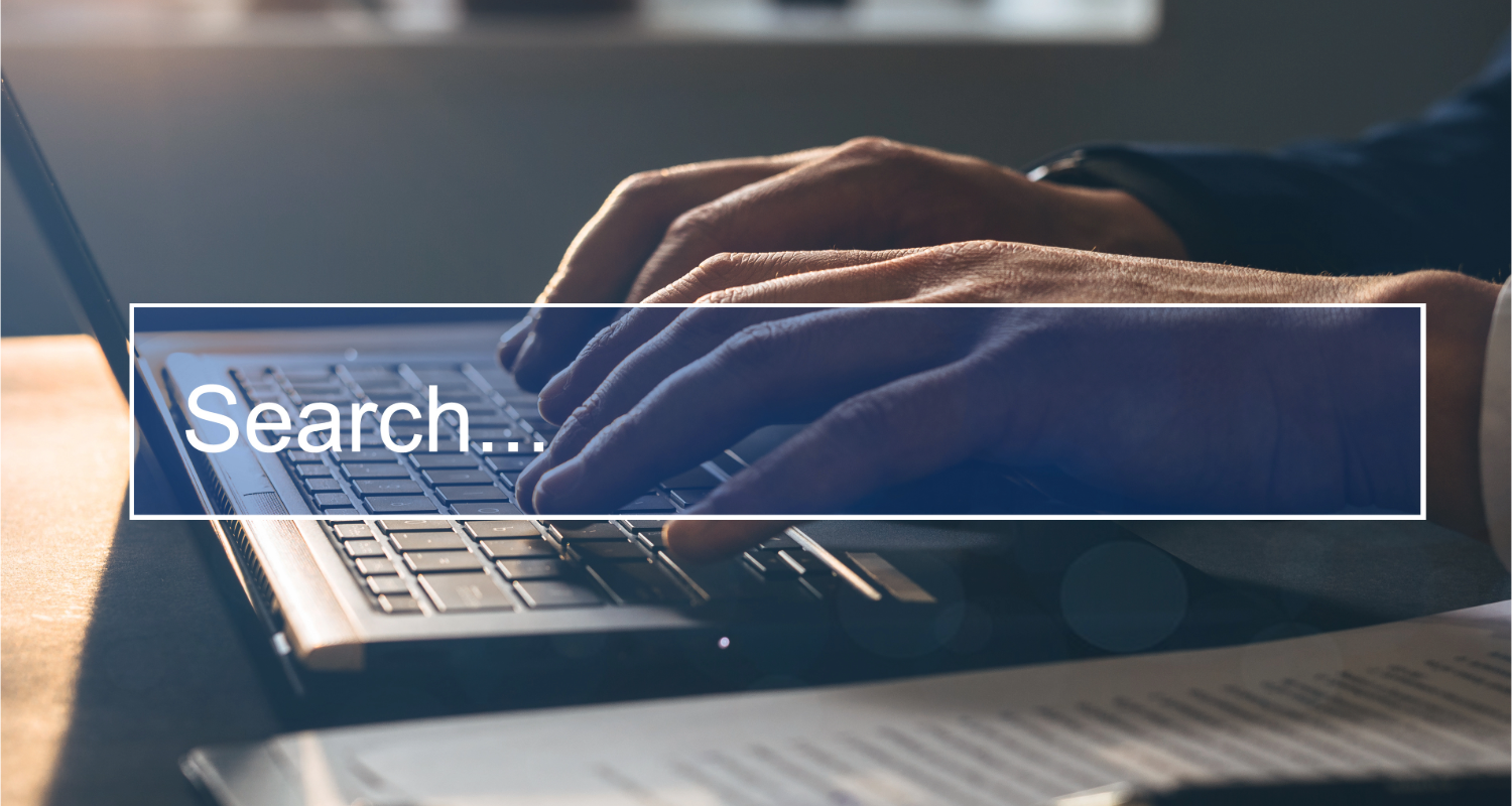 Hands typing on a laptop with a “Search…” text overlay.
